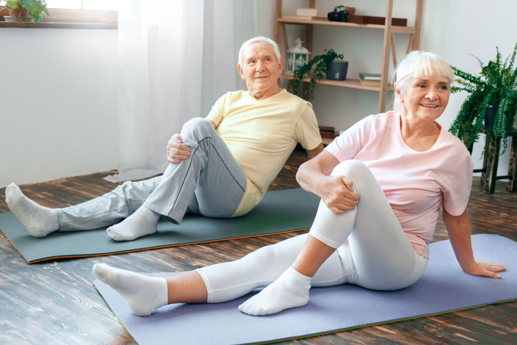 Deux seniors pendant une séance de gymnastique douce sur tapis